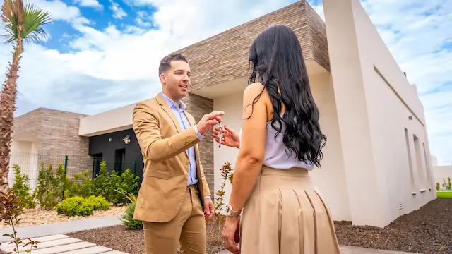 Corretor e proprietária em frente a uma casa