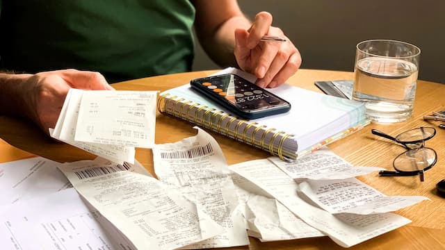 Pessoa organizando contas e calculando despesas para declaração de imóvel no Imposto de Renda.