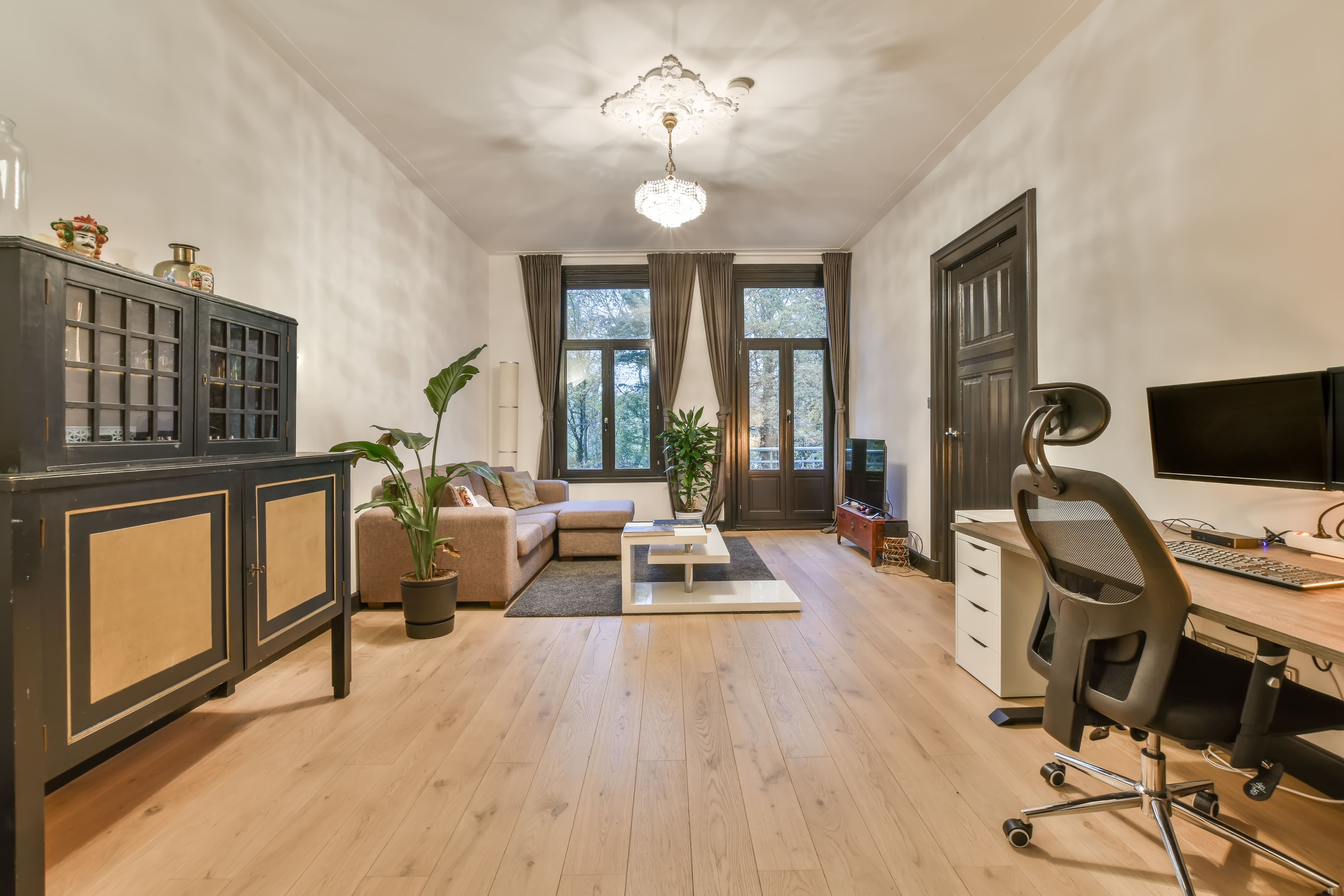 Apartamento limpo e organizado com chão de madeira e móveis em tons de marrom.