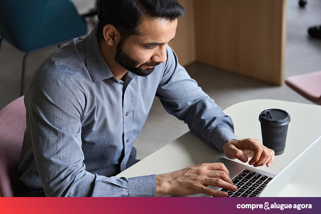 Homem de camiseta social com um notebook em um texto sobre os cursos essenciais para corretores de imóveis